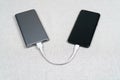 The smartphone is charging from external powerbank with cable