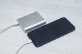 Smartphone charging with power bank on a gray wooden table. Portable charger for charging devices Royalty Free Stock Photo