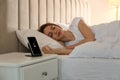 Smartphone charging on wireless pad and woman in bed