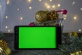 Smartphone with chromakey on the background of Christmas decorations. Bokeh. Chromakey. Space for text