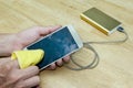 Smartphone cleaning screen with power bank on wood background