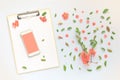 Smartphone and clipboard mock up with floral decoration flat lay