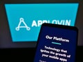 Smartphone with company logo of American mobile technology platform AppLovin Corp. on screen in front of website.