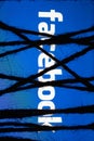 Smartphone in the dark, tightly wrapped and tied with coarse jute rope bondage lies with a glowing blue screen with facebook text