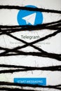 Smartphone in the dark, tightly wrapped and tied with coarse jute rope bondage lies with glowing screen with popular Telegram app