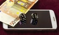 Smartphone, dice poker, and part of fifty euro banknotes