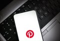 Smartphone displaying Pinterest logo on laptop keyboard illustrative editorial technology and social media Royalty Free Stock Photo