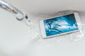 Smartphone dropped into the sink under the water. Concept mobile phone repair. Recessed phone into the water Royalty Free Stock Photo