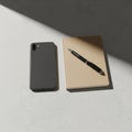 A smartphone with a dual-camera setup, a beige notebook, and a black pen are Royalty Free Stock Photo