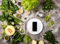 Smartphone on empty plate Different vegetables and herbs.