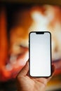 smartphone empty white screen mockup hand hold fireplace warm background Royalty Free Stock Photo