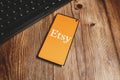 Etsy logotype on phone with keyboard, wooden desk