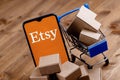 Smartphone with Etsy logo on the screen, shopping cart and parcels Royalty Free Stock Photo