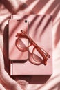 Pink workspace flat lay with smartphone, eyeglasses and notebook Royalty Free Stock Photo