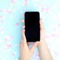 Smartphone in female hands on a blue background with confetti Royalty Free Stock Photo