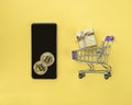 Smartphone and Golden Virtual money bitcoin coin on table with mini shopping cart. Concept of bitcoin payment Royalty Free Stock Photo