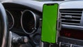 Smartphone or GPS, navigator device in a holder in car with blur background of traffic jams in the evening. Mockup green Royalty Free Stock Photo