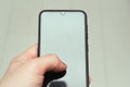 Smartphone in hand close-up. Glossy screen surface. The thumb presses on the gadget screen.