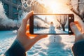 A smartphone in the hands of a tourist taking a photo of a friendly snowman in a city park on a frosty winter day