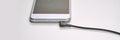 Smartphone with headphone jack connected via cable on white surface Royalty Free Stock Photo