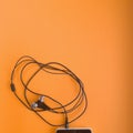 Smartphone and headphones with a 3.5 mm jack on an orange background, flat photography