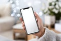Smartphone held in hand with blank screen in cozy indoor setting Royalty Free Stock Photo