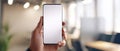 The smartphone held in a hand, showcasing a blank screen in an office environment. AI generated image Royalty Free Stock Photo