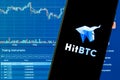A smartphone with the HitBTC logo on the background of the live trading webpage.