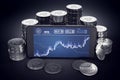 Smartphone with IOTA trading chart on-screen among piles of silver IOTA coins.