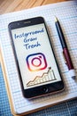 Smartphone displaying Instagram logo and growth chart on a grid notebook with a pen mobile phone Royalty Free Stock Photo