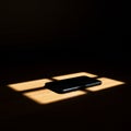 A smartphone lies on a wooden surface, illuminated by a rectangular patch of light Royalty Free Stock Photo