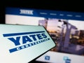 Smartphone with logo of American building company Yates Construction on screen in front of business website.