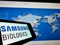 Smartphone with logo of biotechnology company Samsung Biologics Co. Ltd. on screen in front of web page.
