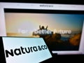 Smartphone with logo of Brazilian personal care company Natura Co Holding SA on screen in front of business website.