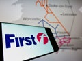 Smartphone with logo of British transport company FirstGroup plc on screen in front of business website.