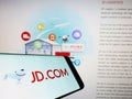 Smartphone with logo of Chinese e-commerce company JD.com Inc. on screen in front of business website.
