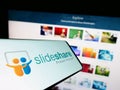 Smartphone with logo of content hosting company SlideShare on screen in front of business website.