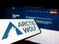 Smartphone with logo of cybersecurity company Arctic Wolf Networks Inc. on screen in front of website.