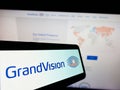 Smartphone with logo of Dutch optical retailing company GrandVision N.V. on screen in front of website.