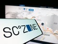 Smartphone with logo of Egyptian Suez Canal Economic Zone (SCZONE) on screen in front of website.