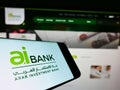 Smartphone with logo of financial company Arab Investment Bank (AIB Egypt) on screen in front of web page.