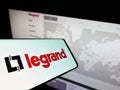 Smartphone with logo of French electronics company Legrand SA on screen in front of business website.