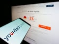 Smartphone with logo of French financial platform company Younited Credit on screen in front of website.