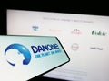 Smartphone with logo of French food company Danone S.A. on screen in front of business website.