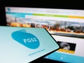 Smartphone with logo of Hungarian gas transmission company FGSZ Ltd. on screen in front of website.