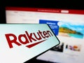 Smartphone with logo of Japanese e-commerce company Rakuten Group Inc. on screen in front of business website.