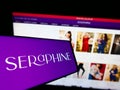 Smartphone with logo of maternity fashion company Seraphine Group plc on screen in front of business website.