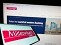 Smartphone with logo of Polish financial company Bank Millennium S.A. on screen in front of business website.