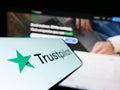Smartphone with logo of review platform company Trustpilot Group plc on screen in front of business website.