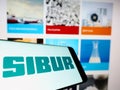 Smartphone with logo of Russian petrochemicals company SIBUR Holding PJSC on screen in front of business website.